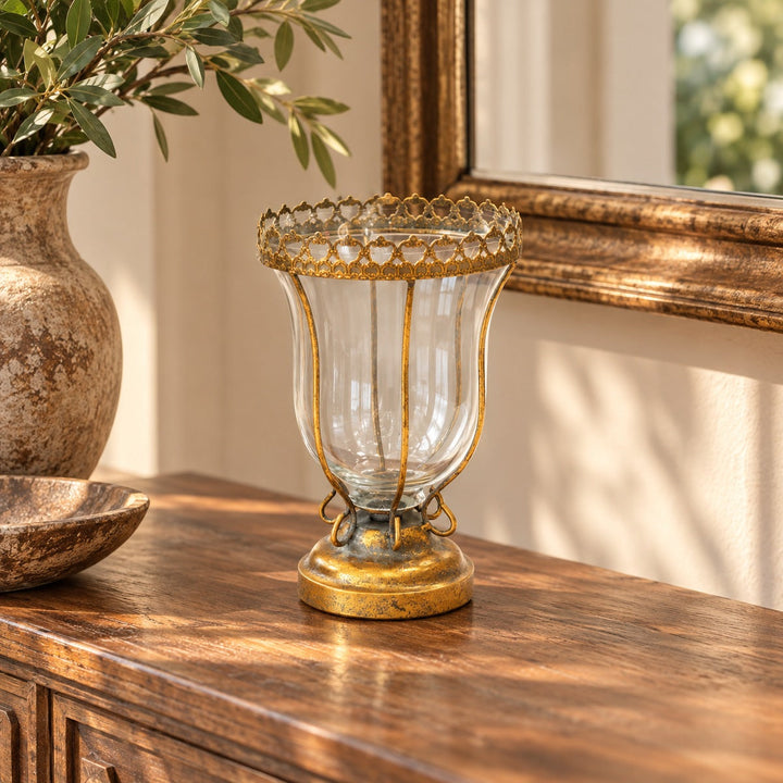 Copa decorativa de vidrio y metal dorado envejecido sobre consola en recibidor