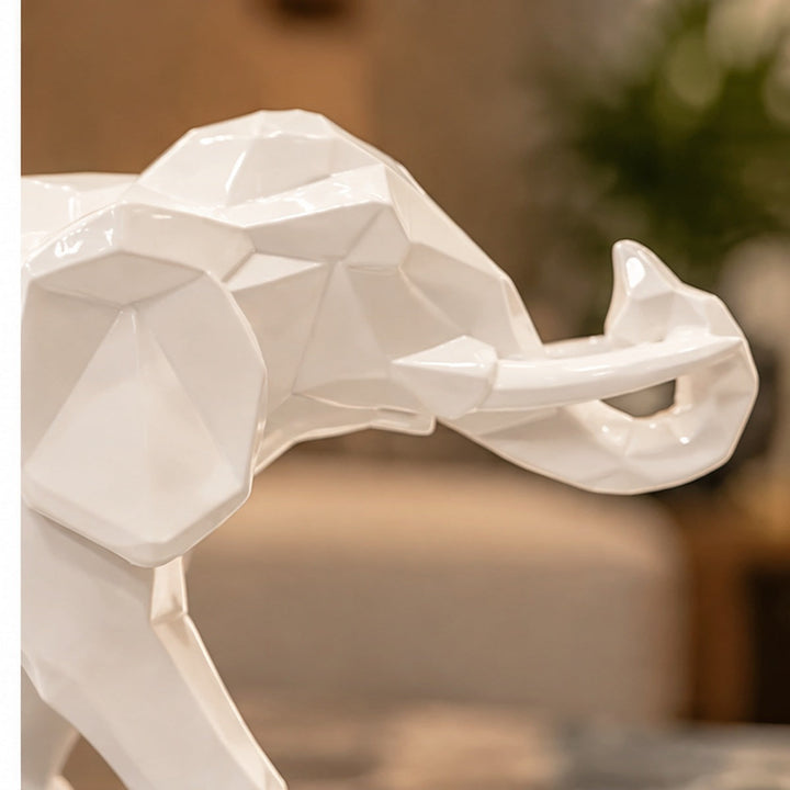 Detalle del elefante blanco brillante de resina con facetas geométricas y trompa levantada