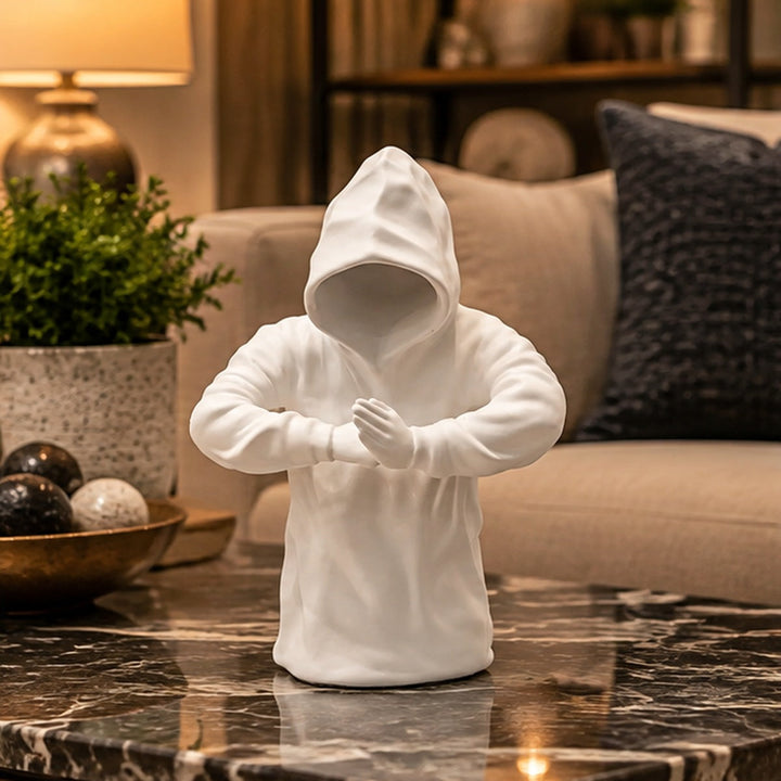 Escultura blanca con capucha y manos juntas en living