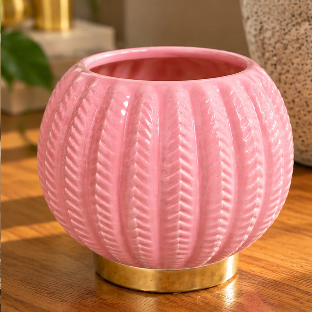 Detalle del florero rosado con relieve de hojas y base dorada