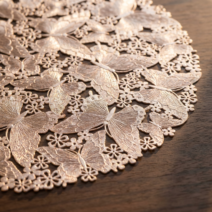 Detalle del calado de mariposas y flores del individual oro rosa