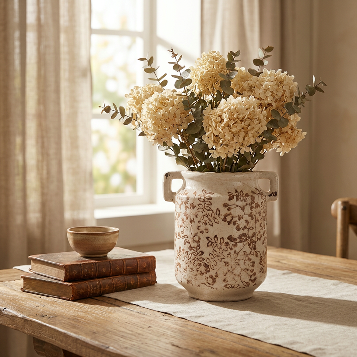 Jarrón vintage con asas y hortensias secas en mesa de comedor