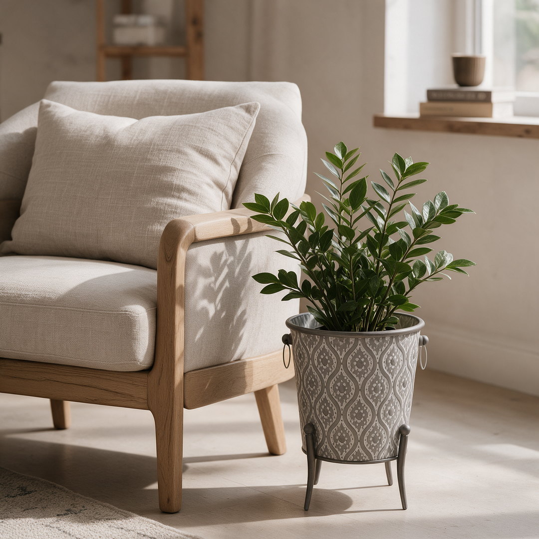 Porta maceta cilíndrico gris mate tamaño mediano junto a sillón Casona Deco