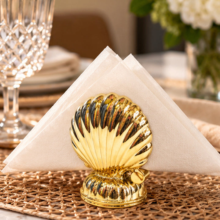 Servilletero almeja dorado en mesa elegante